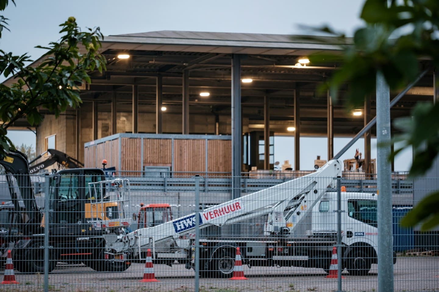 Byggemaskiner står bak et gjerde på en byggeplass.